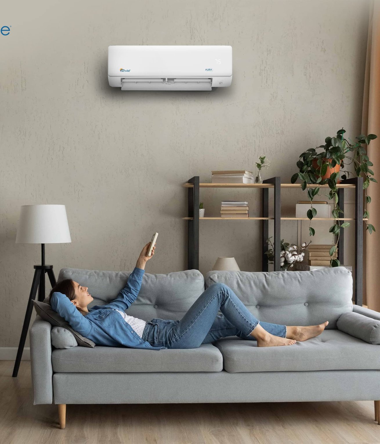Wall-mounted Senville AURA mini split above a grey sofa in a bright living room with a homeowner relaxing