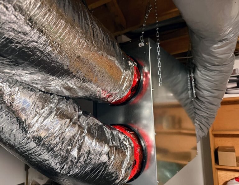 Two insulated flexible ducts clamped to a sheet-metal plenum box with red sealing tape inside a utility space