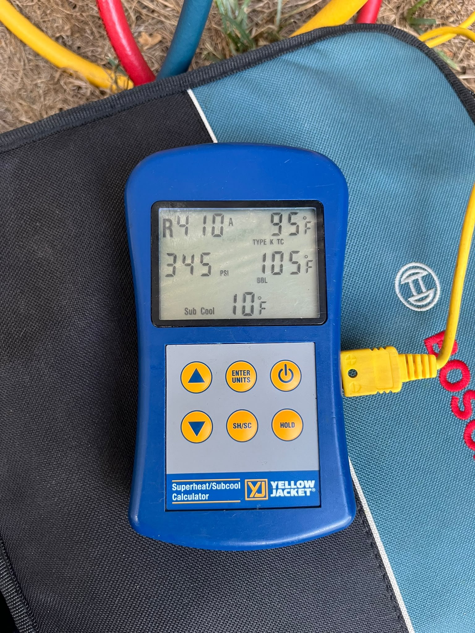 Yellow Jacket superheat and subcool calculator showing R410A, 345 psi and 10 degree subcooling on a gauge bag