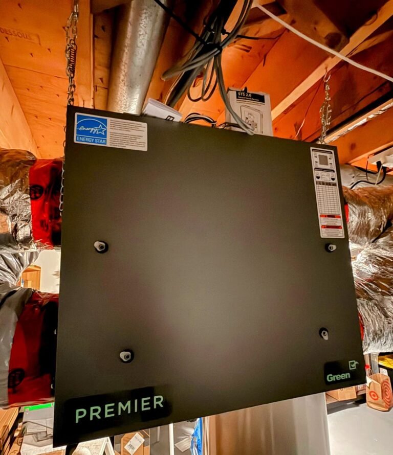 Large ventilation unit hung from basement ceiling joists with a black EnerGuide label and a green logo